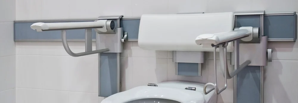 Barrierefreies WC mit hochklappbaren Stützgriffen an der Wand.